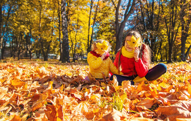 Autumn child in the park with yellow leaves. Selective focus.