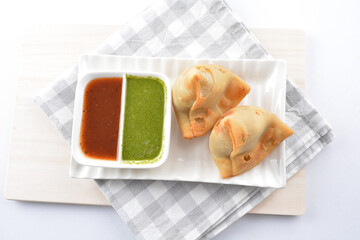 deep fried indian curry potato vegetable samosa snack with green mint yogurt sauce on white background vegan appetiser dim sum snack Halal food restaurant cuisine menu for cafe
