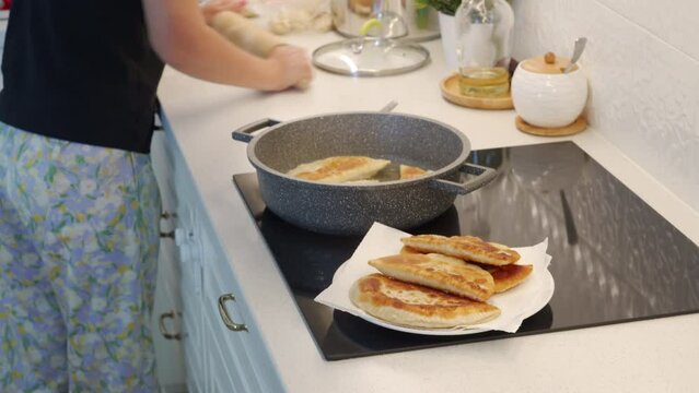 woman cooking homemade pasties frying chebureks in the kitchen at home