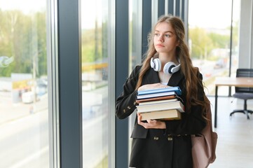 Portrait of a schoolgirl standing in the classroom with a book in her hands.