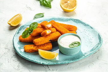 Crispy breaded deep fried fish fingers with breadcrumbs served with sauce and lemon. Food recipe...