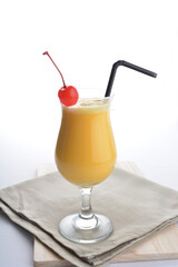 cold iced summer orange mango fruit juice with red cherry in cocktail glass black straw on grey cloth white background asian beverage halal food drink menu for hotel bar cafe