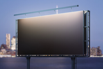 Obraz premium Blank black horizontal billboard on city buildings background at night, perspective view. Mockup, advertising concept
