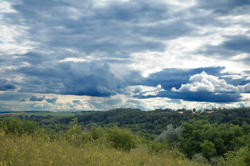 Landscape image of countryside of Ukraine. Cloudy sky, grassy fields and rolling hills rural scenery