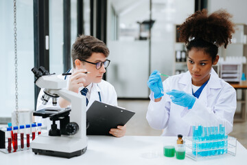 Focused mature male doctor and African female nurse look at tablet and laptop screen discuss anamnesis together. Concentrated diverse medical professionals