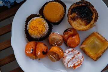 Mix of traditional Portuguese egg yolk sweets from Porto region on white plate with blue hydrangea...