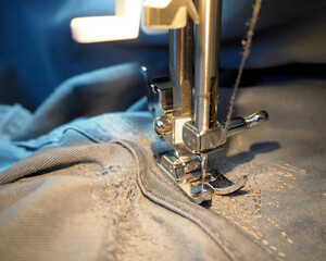 the process of repairing men's dark blue denim trousers on a sewing machine. side view . sewing...