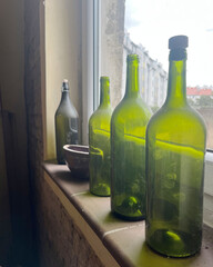 three green empty bottles stand on the window in the corridor. interior