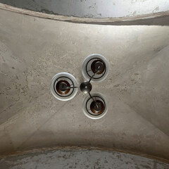 an old white chandelier on a shabby ceiling in the front door of an old house. bottom view