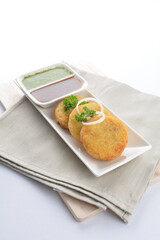 Indian deep fried round potato snack hash brown with green yogurt and red chilli sauce breakfast on white background asian chef appetiser halal bakery food restaurant pastry menu for cafe