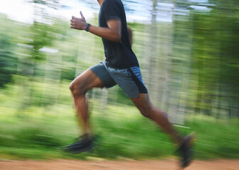 Running, speed and blur of man in forest for marathon training, exercise and cardio workout....