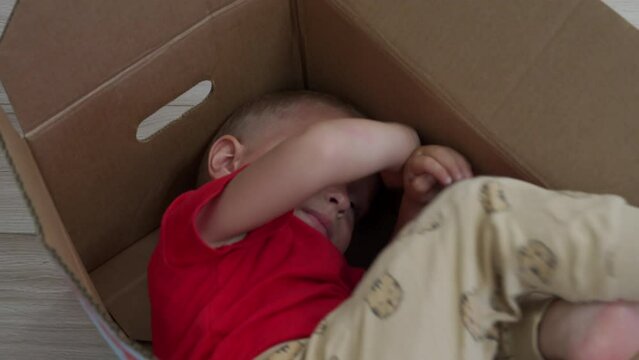 toddler child hiding in cardboard diaper box