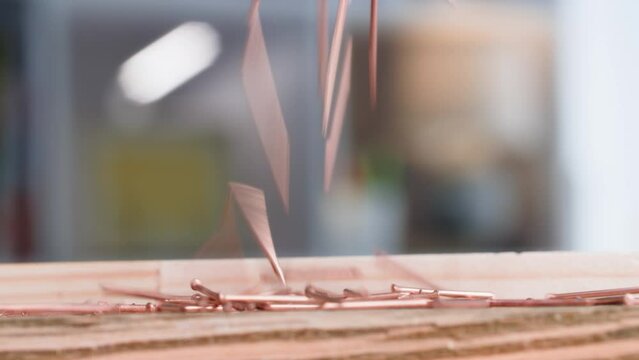 building materials, a bunch of copper nails fall on a wooden board, close-up