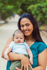 Latin woman with her baby in a park looking at the camera