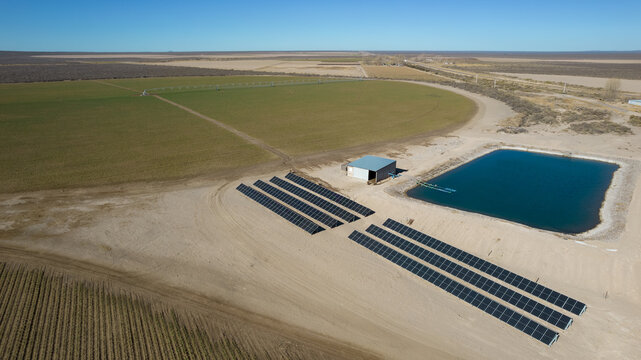 Solar pumping system, for irrigation in pivot plantations. In the desert of Mendoza, Argentina. Aerial view of solar panels and water pool.