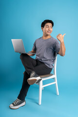 Full body young  Asian man using laptop on blue background