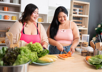 Happy Asia plus size woman cooking salad in kitchen at home	