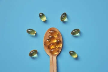 Yellow capsules on a wooden spoon, vitamin D