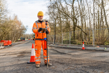 Site engineer operating his touch screen controller instrument during roadworks. at construction...