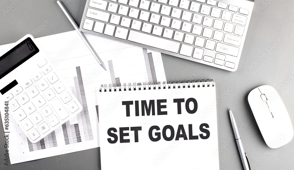 Poster time to set goals text written on notebook on grey background with chart and keyboard , business con