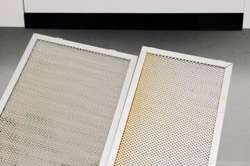 Two dirty aluminum grease filters for range hood against hood backdrop. Concept of clogged filters,...
