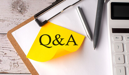 Q A word on yellow sticky with calculator, pen and clipboard
