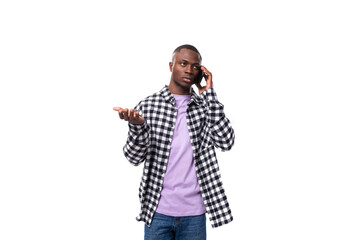 attractive young african man in a plaid shirt talking on the phone on a white background with copy space