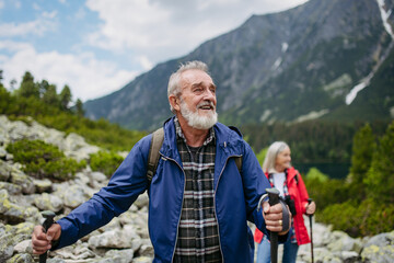 Potrait of active senior man hiking with wife in autumn mountains.