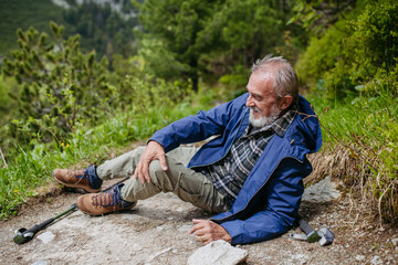 Senior man injured his leg during hike in the mountains.