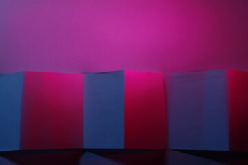Papel vegetal para cocina y preparaciones culinarias, con doblez formando un muro de cubos y rectángulos con luz azul y roja intercalados,  forma un bonito diseño abstracto con fondo rosa - obrazy, fototapety, plakaty