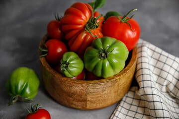 Red and green tomatoes in a basket on a damp background 