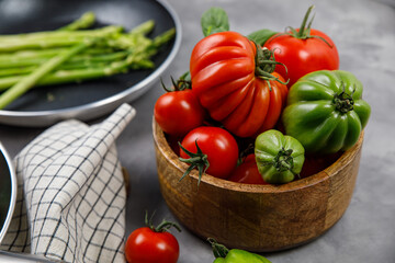 Red and green tomatoes in a basket on a damp background 