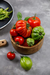 Red and green tomatoes in a basket on a damp background 