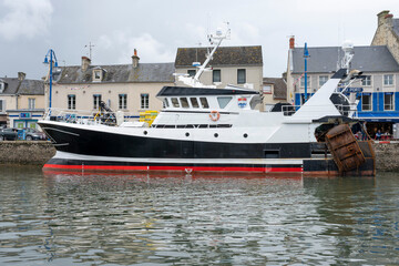 Port-en-Bessin-Huppain, France - 07 24 2023: A blue fishing boat entering the harbor.