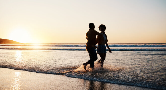 Beach sunset, sea water and silhouette couple walking, connect or enjoy romantic holiday in South Africa. Love, ocean waves and dark shadow of summer people bond, talking and relax on evening journey