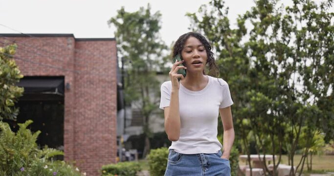 African American teenage girl walking in the garden talking on the phone. modern communication technology smartphone high speed internet. Take a walk during the holidays