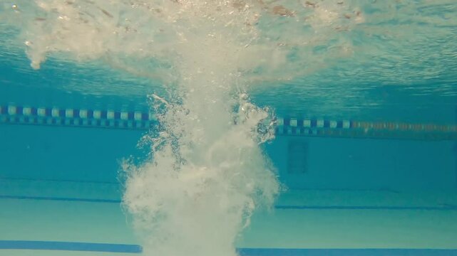 Woman athlete swims underwater in the pool. Slow motion of a female swimmer in the pool during training. The swimmer dives deep underwater.