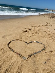 Corazón en la orilla de playa hecho de piedras