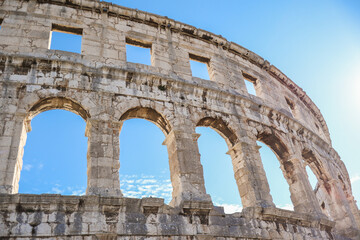 Fototapeta premium Roman Amphitheater with Arch Window in Croatia. Pula Arena Landmark with Blue Sky. European Monument Outside.