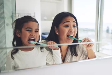 Acrylglasbilder Zahnärzte Mother, child and brushing teeth in dental hygiene, morning routine or healthcare together by mirror in bathroom. Happy mom and daughter cleaning mouth in tooth whitening, oral or gum care at home  © Azee/peopleimages.com