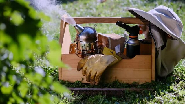 Work at the apiary. A tool of the beekeeper. Everything for a beekeeper to work with bees. Smoker, a chisel, a box, beekeeper suit for protection from the bees. Beekeeping equipment.