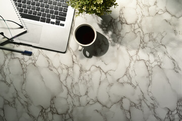 Top view workspace with laptop, coffee, notebook on marble table.