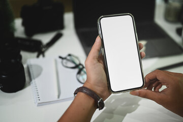 Cropped shot photography holding empty screen of smartphone on workspace.