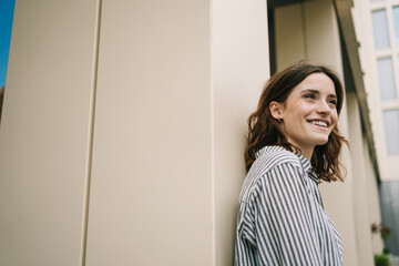 Happy Young Woman Leaning Against Modern Building