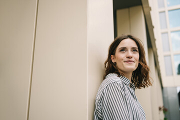 Young Woman Positively Gazing Upwards by Modern Building