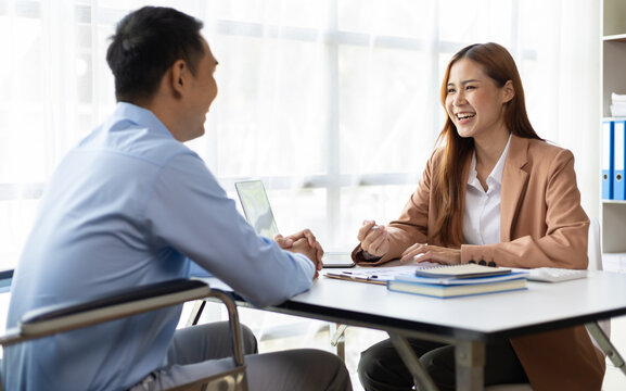 Man in wheelchair talking to female manager in office about recruitment and job interview.