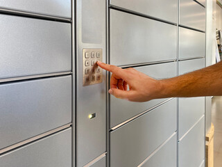 A man presses buttons on a self-service terminal for automatic parcel delivery
