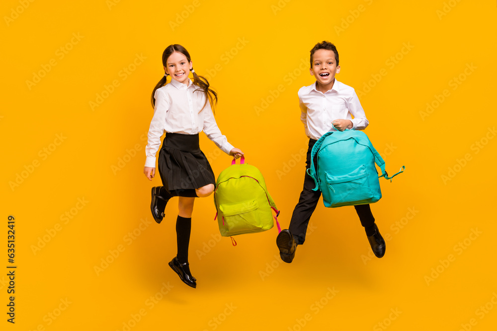 Poster full length photo of cheerful funky preteen schoolkids dressed white shirts holding rucksacks isolat