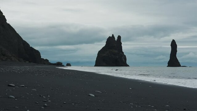Reynisdrangar basalt sea stacks on Reynisfjara black sand beach near Vik town in summer