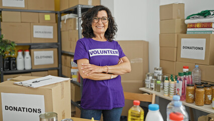 Middle age hispanic woman volunteer smiling confident standing with arms crossed gesture at charity center